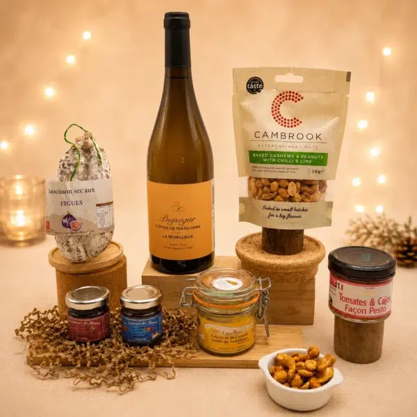 Panier garni apéritif composé d'un vin moelleux de Gascogne, foie gras entier, saucisson à la figue, tartinables artisanaux et assortiment de fruits secs dans une ambiance chaleureuse de fin d'année.